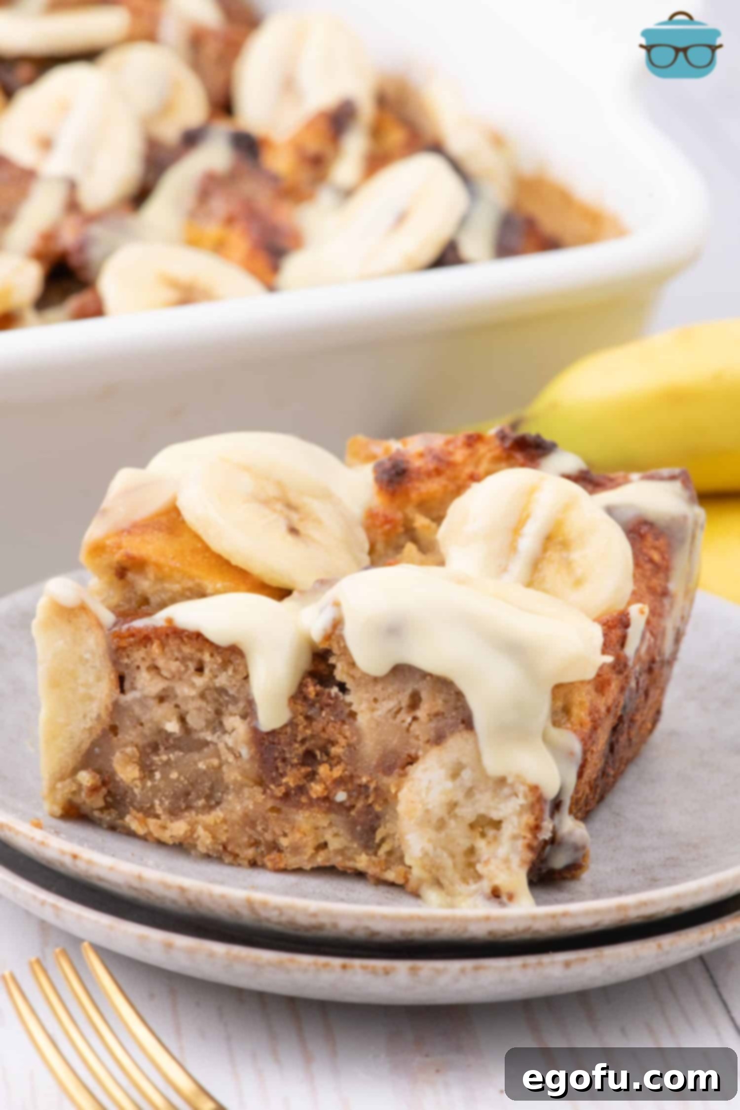 A big slice of Banana Bread Pudding on a dessert plate, showcasing its golden crust and creamy interior.