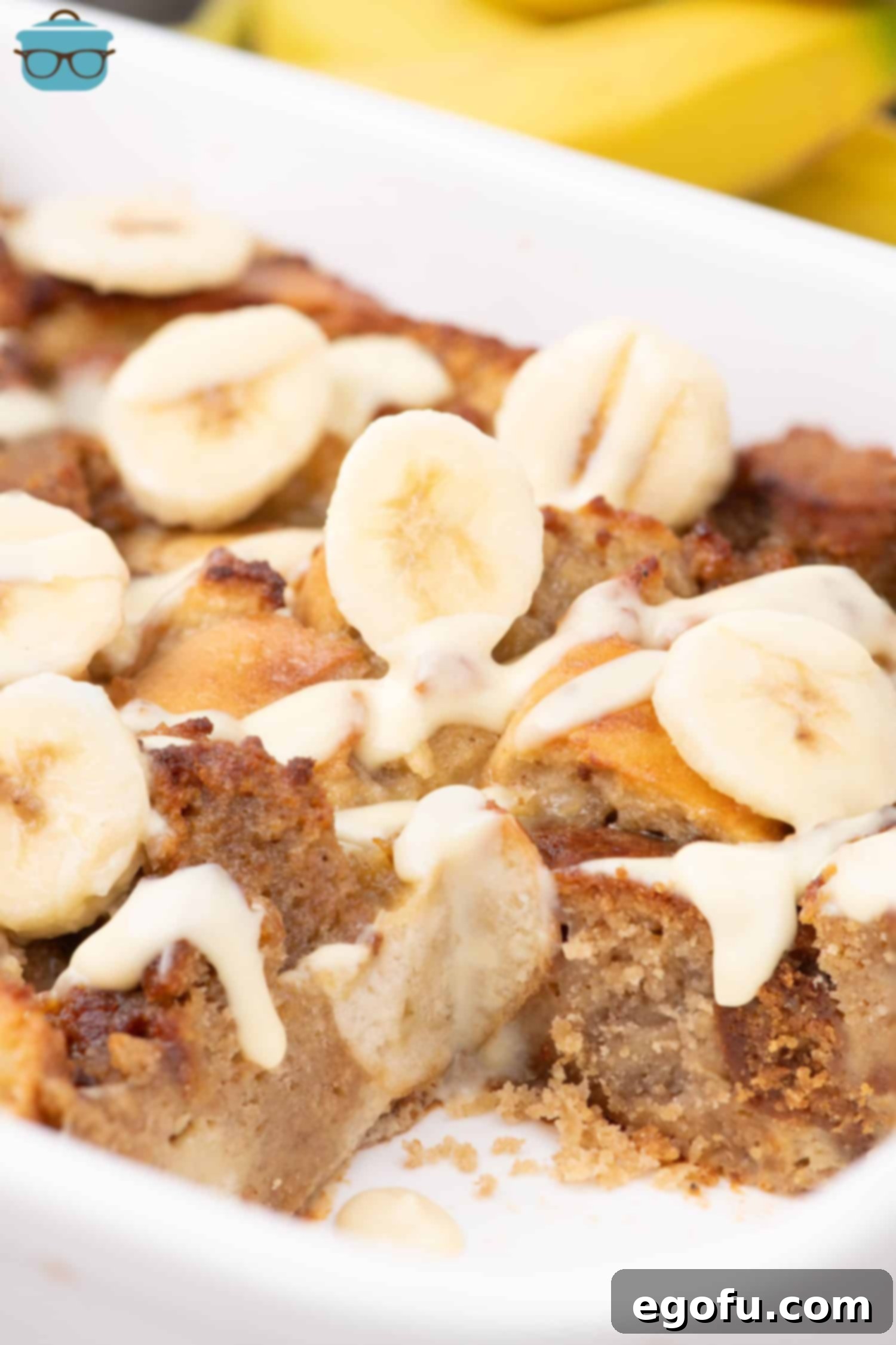 A baking dish with a slice of Banana Bread Pudding missing, indicating it's ready to be enjoyed.