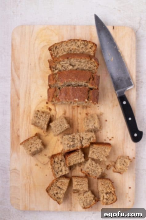 Cubed banana bread with the rest of the loaf on a cutting board.