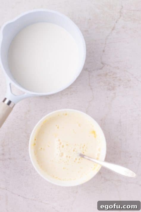 Vanilla cream mixture being mixed with egg yolks and sugar.