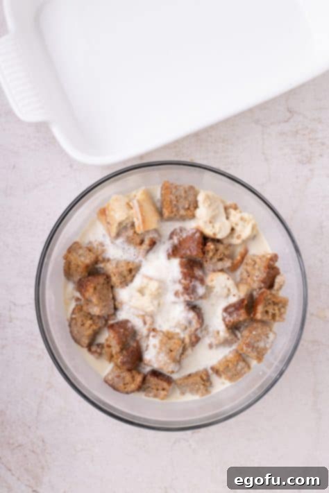 Bread pieces and banana custard soaking together in a large mixing bowl.