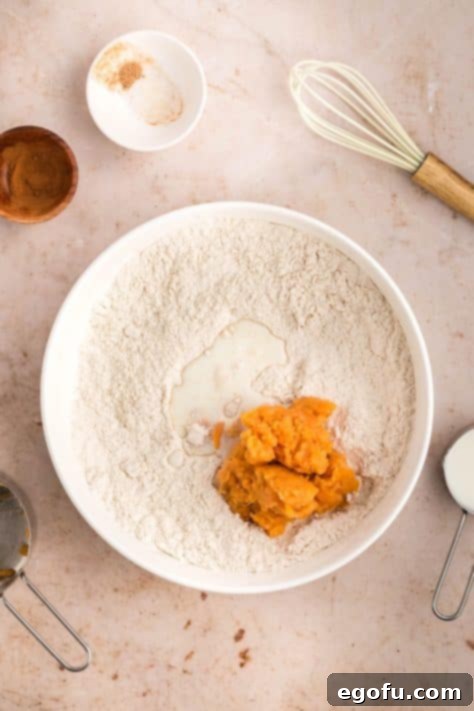 Mashed yams being added to dry ingredients in a bowl.