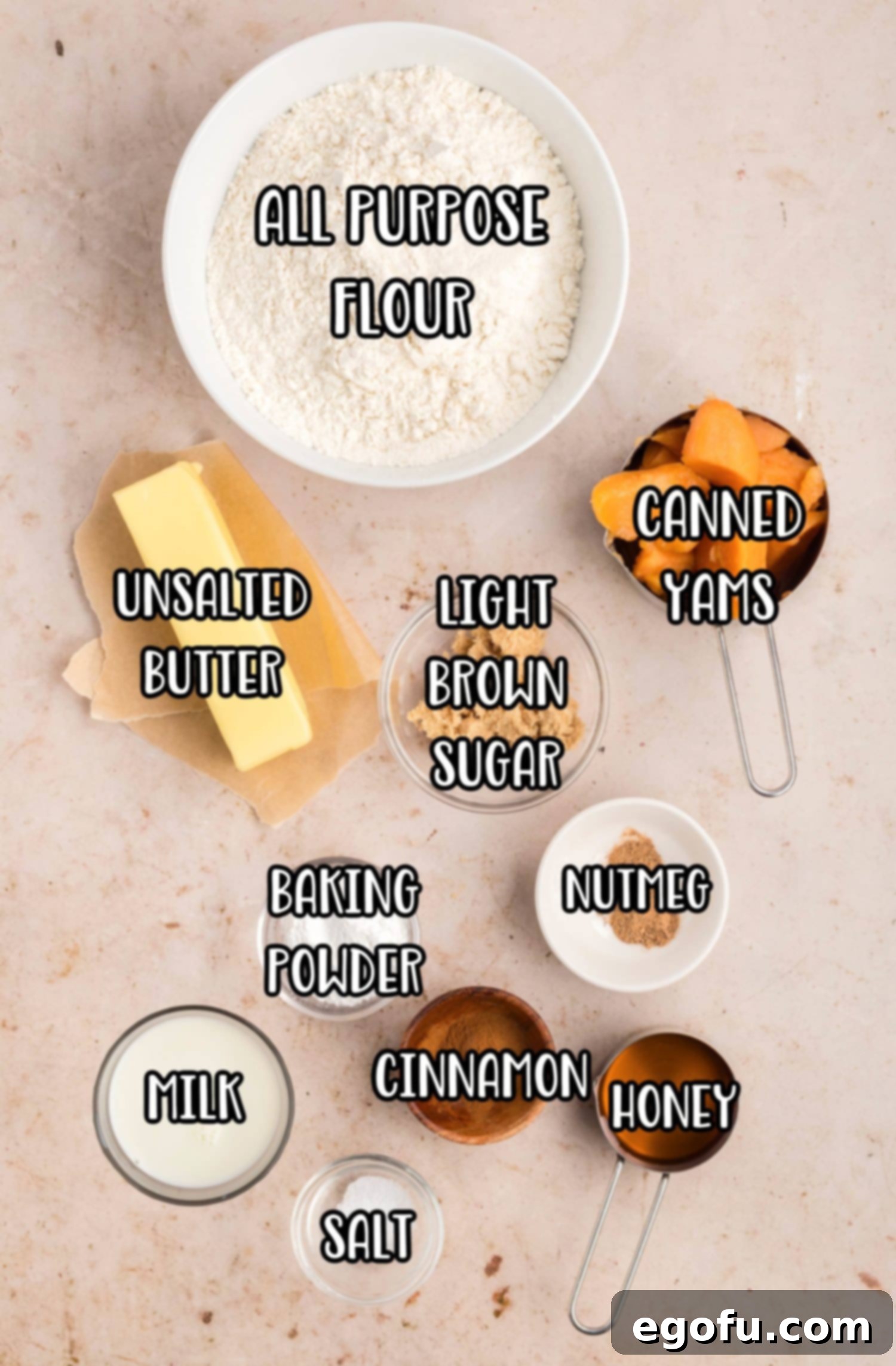 A vibrant flat lay of all the essential ingredients: all-purpose flour, canned yams, butter, light brown sugar, nutmeg, baking powder, cinnamon, honey, milk, and salt, artfully arranged for Sweet Potato Butter Swim Biscuits.