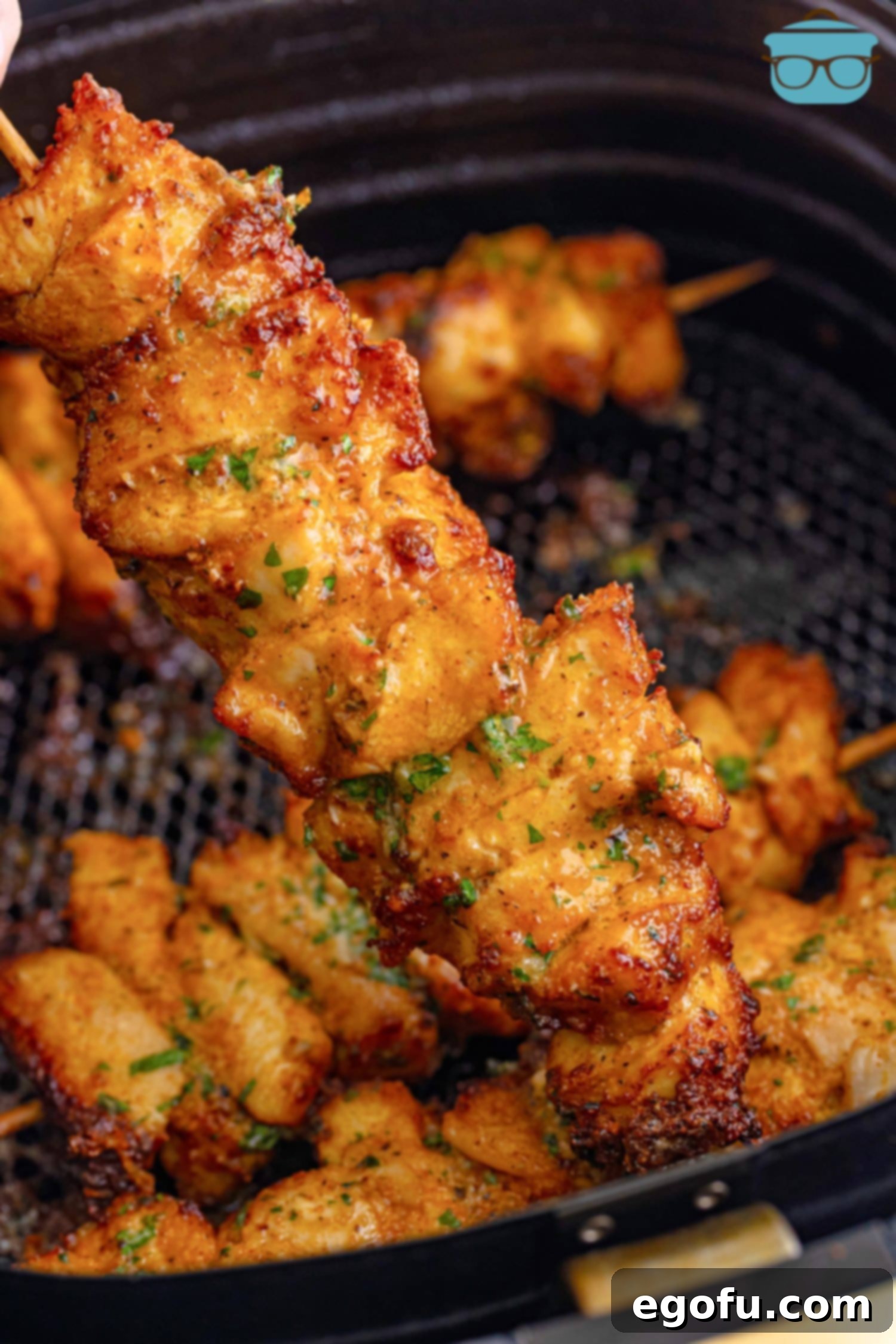 Several golden brown Air Fryer Garlic Parmesan Chicken Skewers arranged in an air fryer basket, ready to be served.