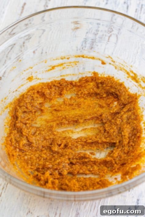 A bowl with mayonnaise, parmesan, olive oil, Montreal chicken seasoning, garlic powder, cajun seasoning, and paprika.