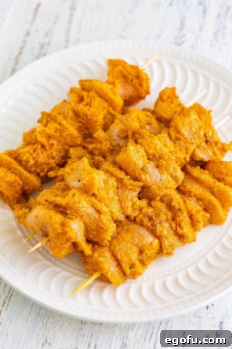 Raw chicken skewers on a plate.