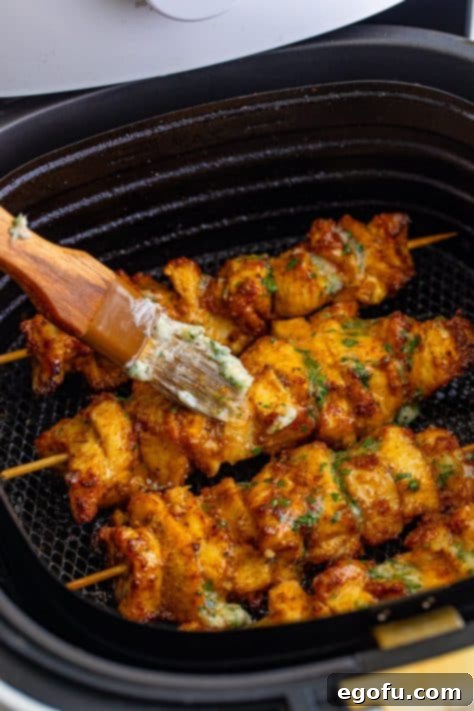 Garlic Butter sauce being added to chicken skewers in an Air Fryer basket.