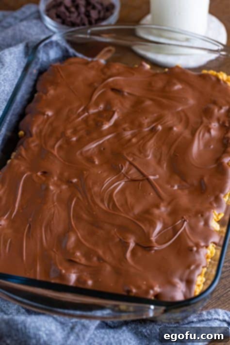 Crispy Peanut Butter Dream Bars 24 Chocolate mixture on top of cereal mixture in a pan.