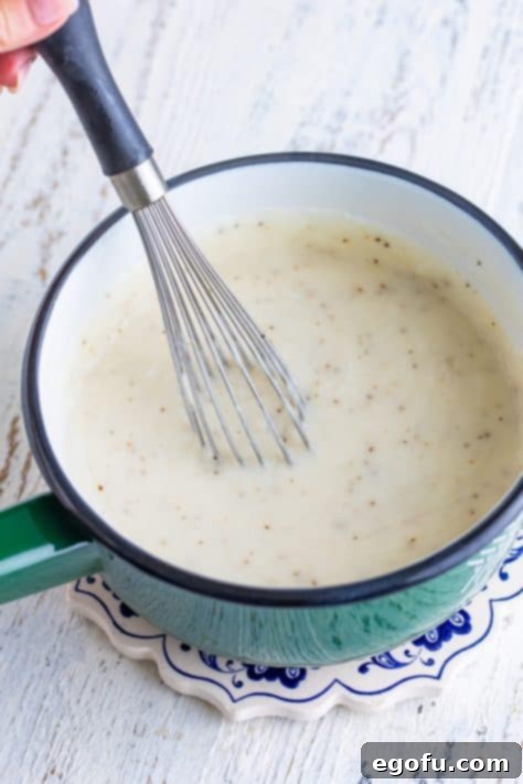 Breakfast gravy in a pan with a whisk.