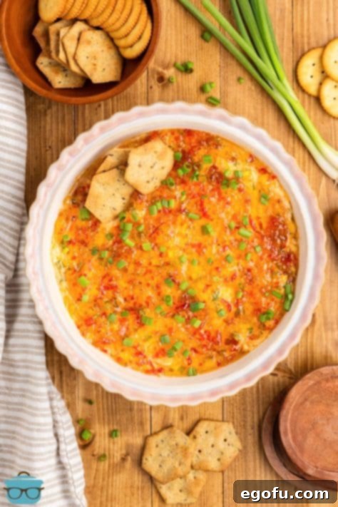 Looking down on a freshly baked pie plate of Pepper Jelly Cream Cheese Dip, beautifully garnished with green onions.