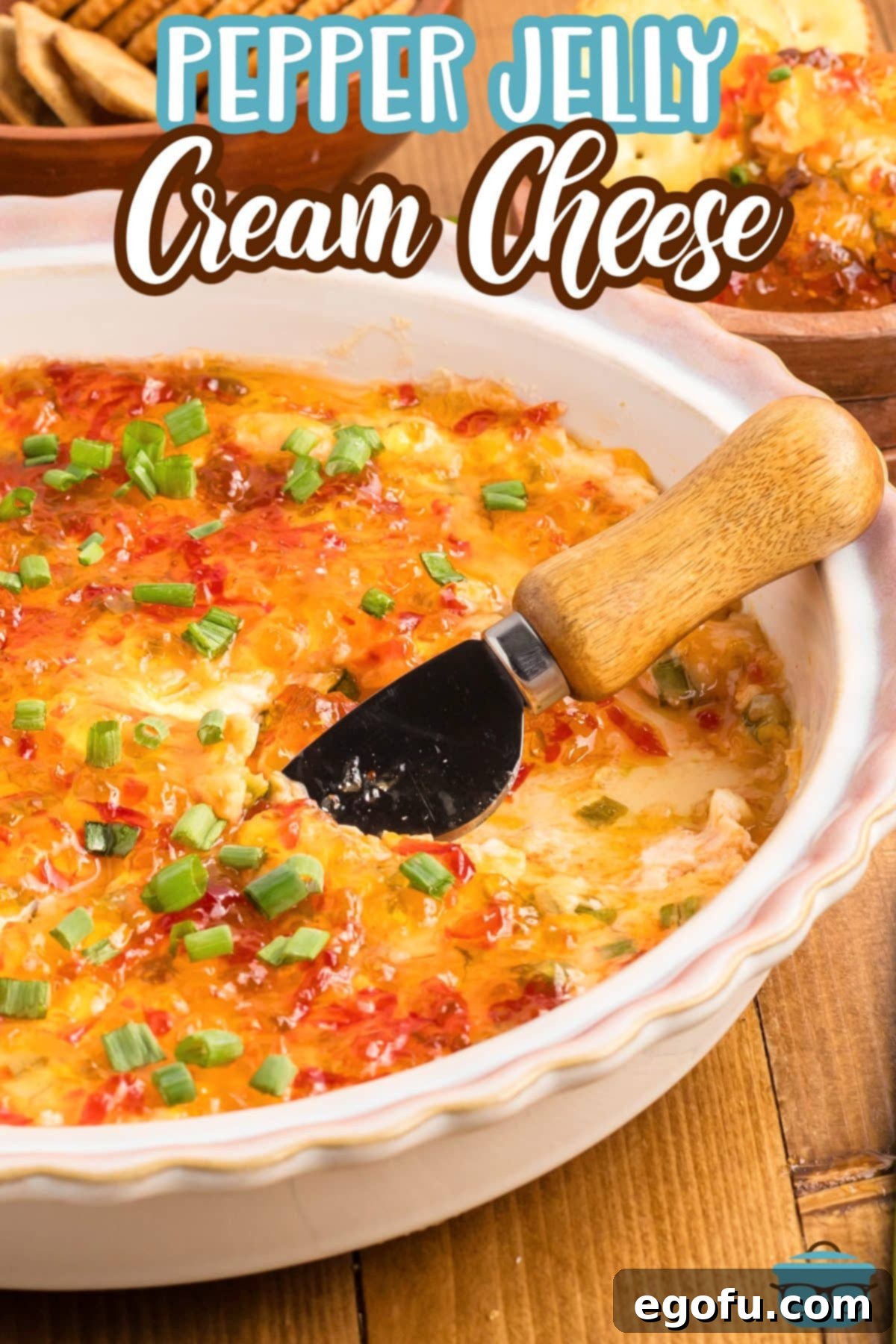A cheese knife in a bowl of warm Pepper Jelly Cream Cheese, inviting you to indulge in its rich flavors.
