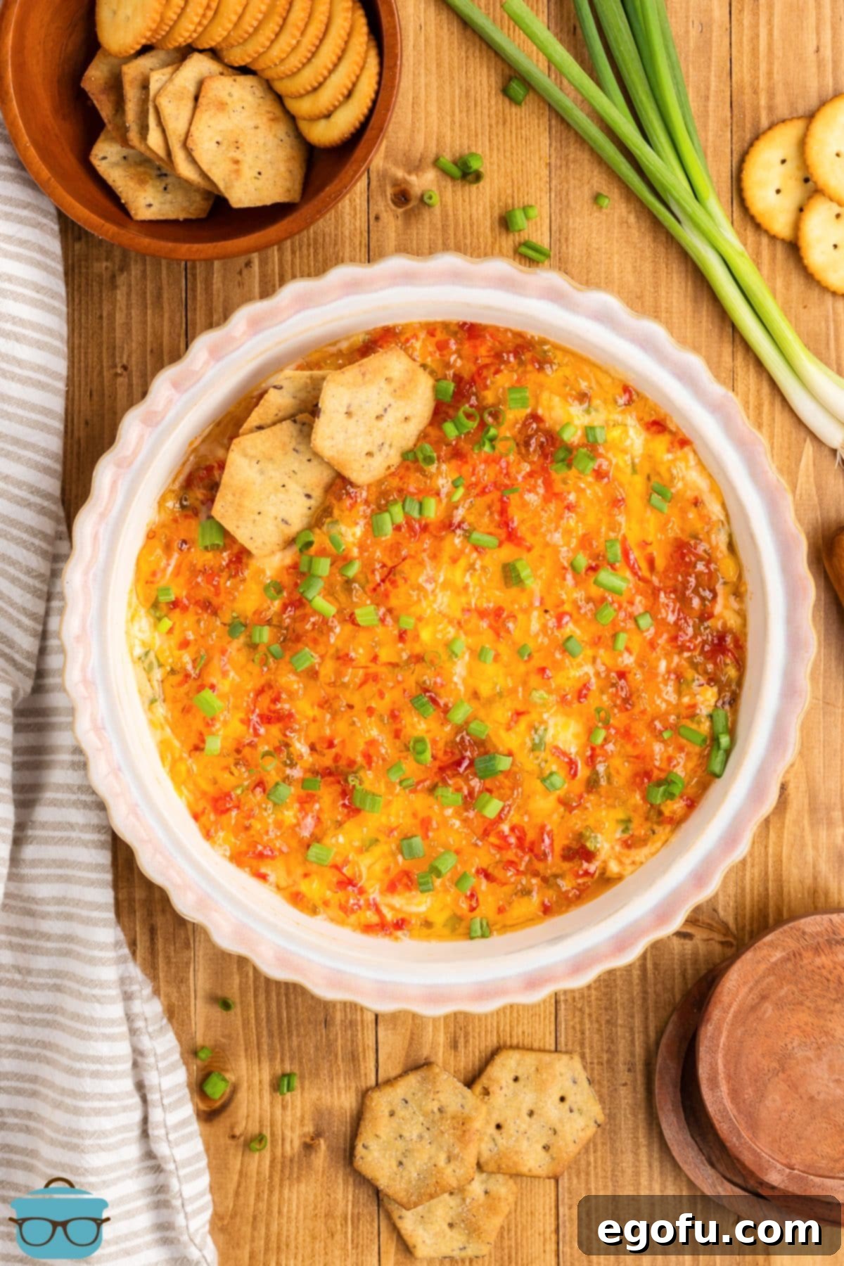 Looking down on a freshly baked pie plate of Pepper Jelly Cream Cheese Dip, garnished with vibrant green onions and ready for serving.