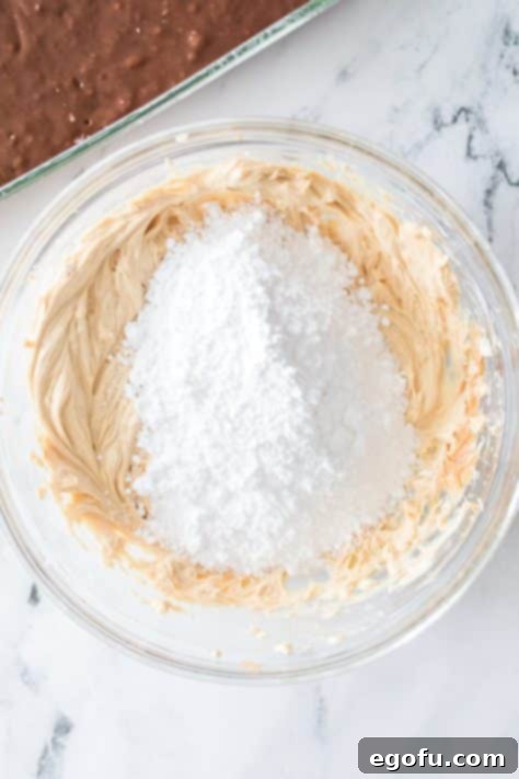 Powdered sugar being added to a cream cheese mixture.