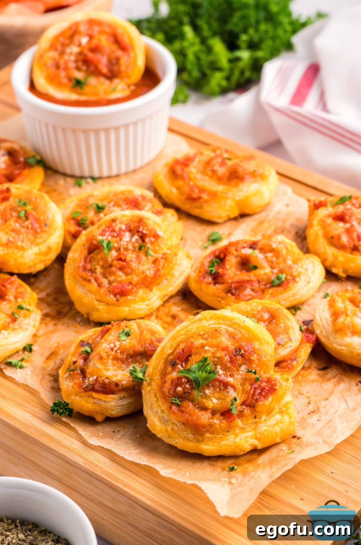 A pile of golden-brown Pepperoni Pinwheels on a piece of wax paper, showcasing their flaky crust and savory filling.