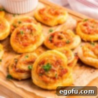 Closely looking at a few Pepperoni Pinwheels on a wooden board, highlighting their flaky layers.