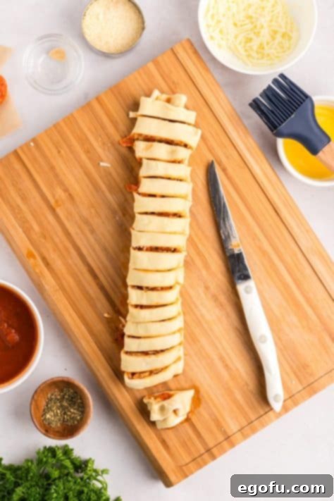 A pepperoni roll log being cut into slices on a cutting board.