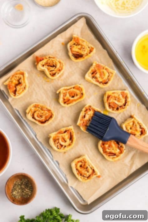 Unbaked pinwheels brushed with egg wash and sprinkled with Parmesan cheese.