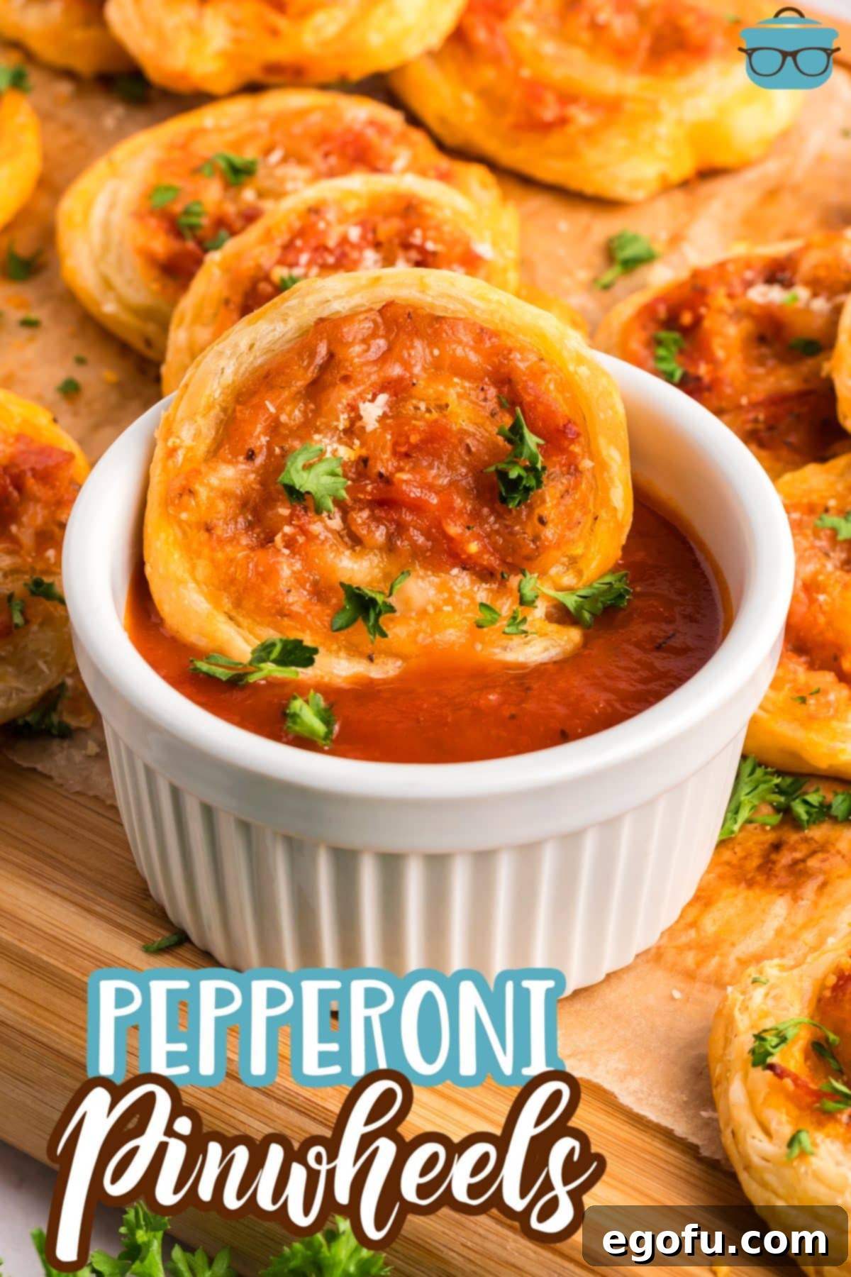 A few freshly baked Pepperoni Pinwheels arranged in front of a ramekin of marinara sauce, with one pinwheel being dipped.