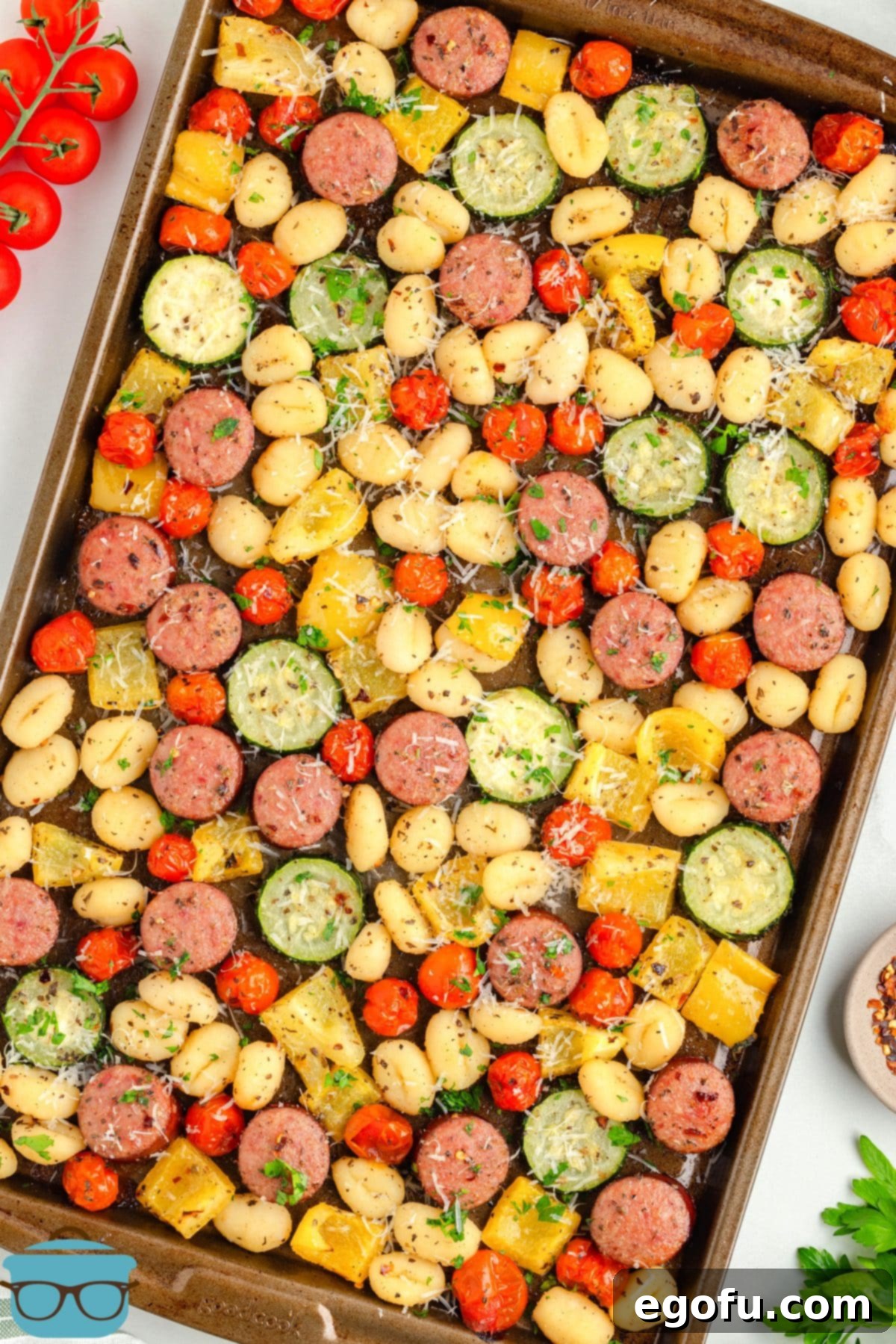 One-Pan Sausage and Gnocchi Bake 2 A vibrant sheet pan filled with golden-brown gnocchi, sliced smoked sausage, and colorful roasted vegetables like yellow bell peppers, zucchini, and cherry tomatoes, ready to be served.