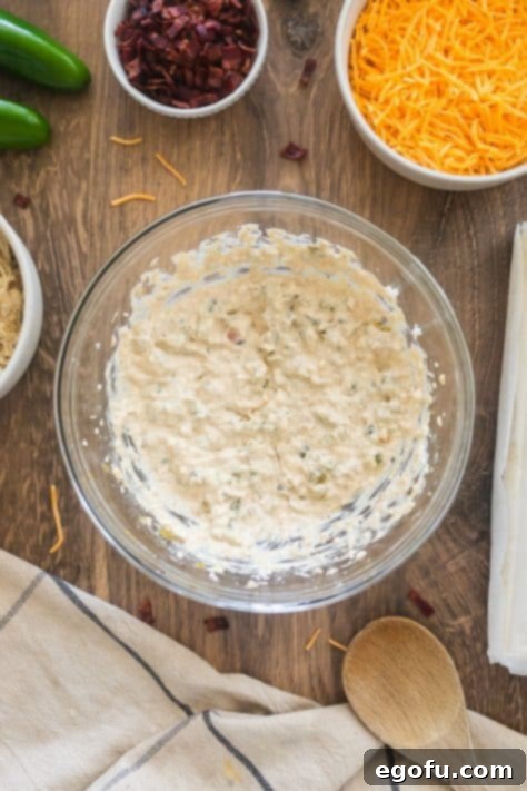 A bowl with cream cheese, jalapenos, onion powder, garlic powder, seasoned salt, poultry seasoning, and chili powder.
