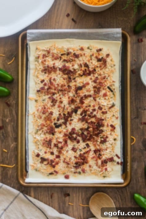 Crumbled bacon sprinkled over a cream cheese mixture on a piece of puff pastry.