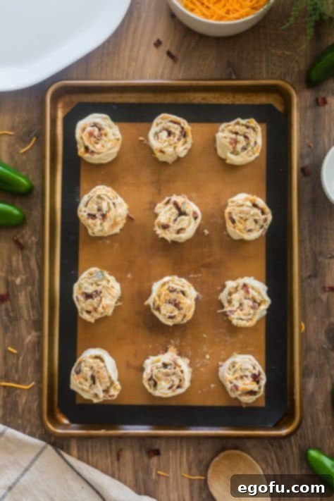 Twelve evenly cut pinwheels on a baking sheet.