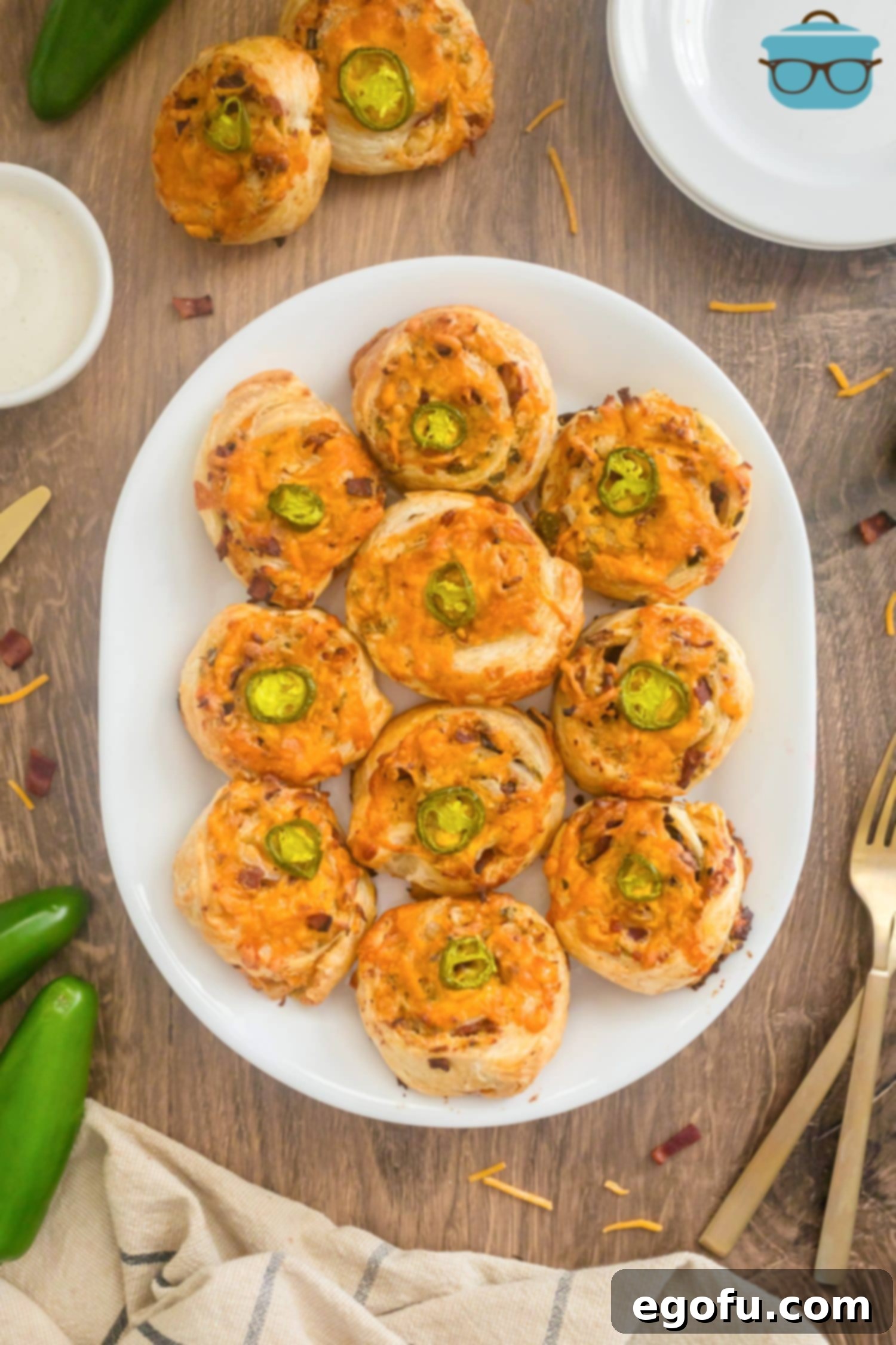 A top-down view of a generously filled serving platter showcasing freshly Baked Jalapeño Popper Pinwheels, golden and inviting.