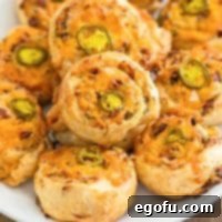 A plate of golden Baked Jalapeno Popper Pinwheels, showcasing their flaky pastry and cheesy filling.