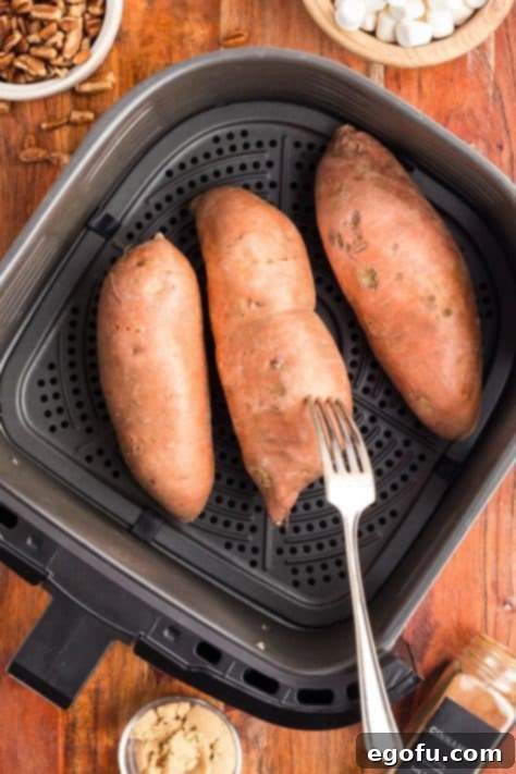 A fork poking holes in sweet potatoes.