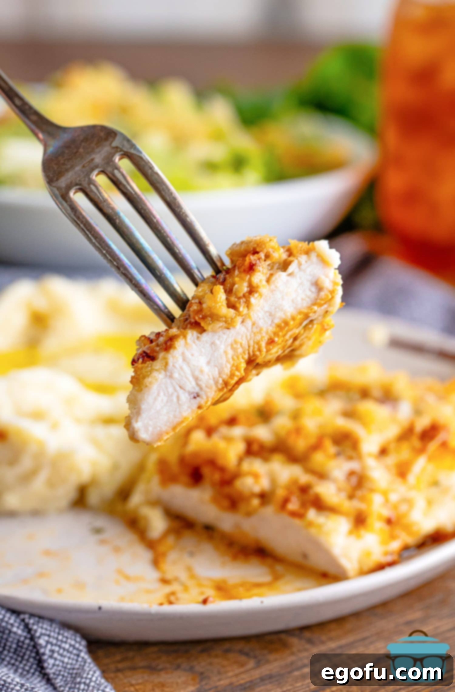 Longhorn's Crispy Parmesan Crusted Chicken 11 A fork holding a bite of Longhorn Steakhouse Parmesan Crusted Chicken.