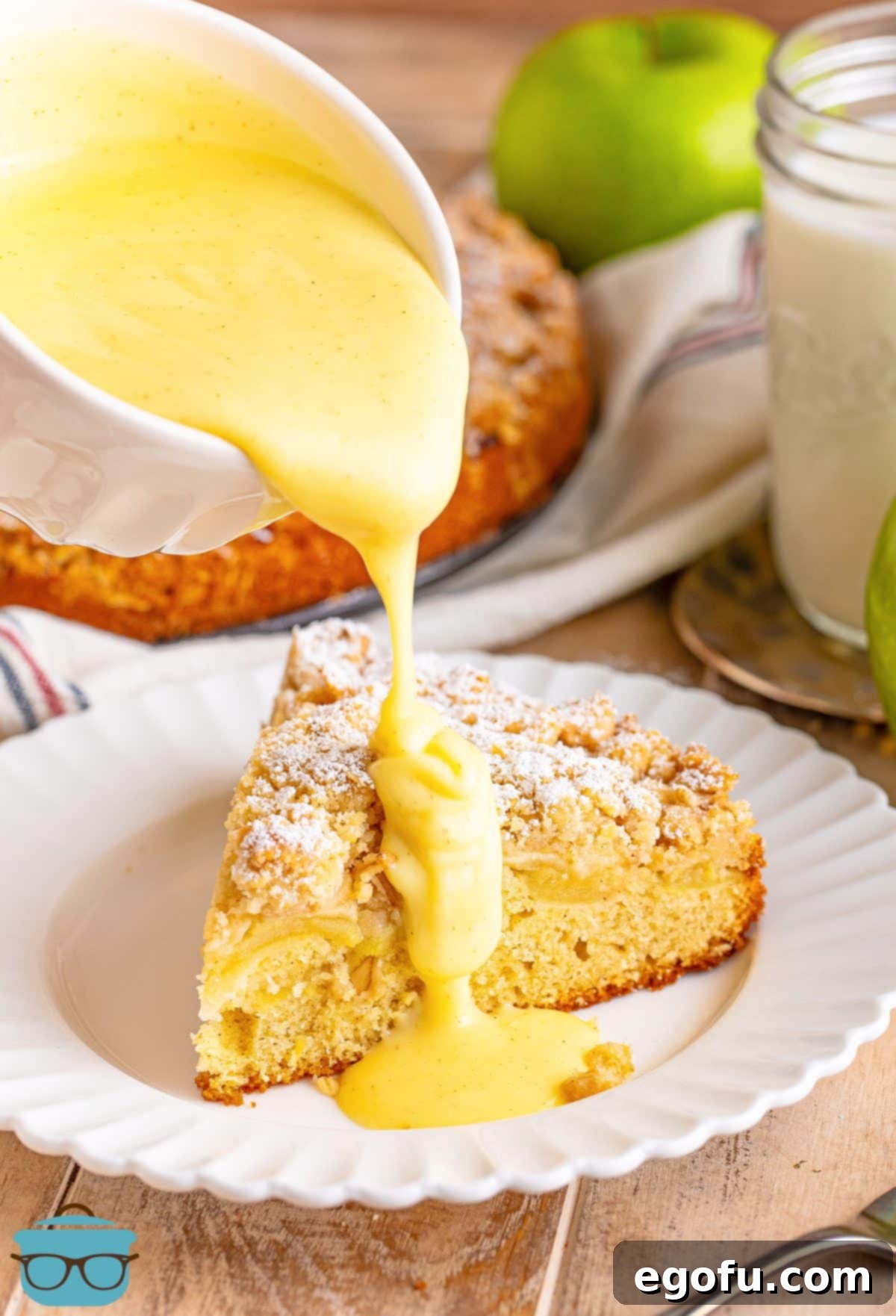 A slice of Irish Apple Cake being drizzled with a creamy custard sauce.