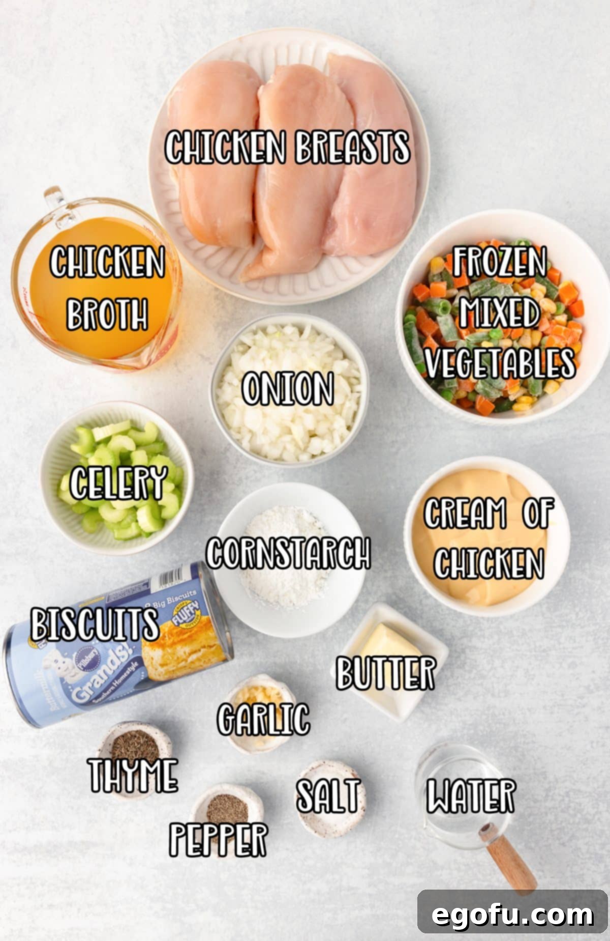 A vibrant flat lay showcasing all the essential ingredients for Instant Pot Chicken Pot Pie: chicken breasts, butter, onion, celery, garlic, chicken broth, frozen mixed vegetables, cream of chicken soup, dried thyme, salt, black pepper, cornstarch, cold water, and refrigerated biscuits.