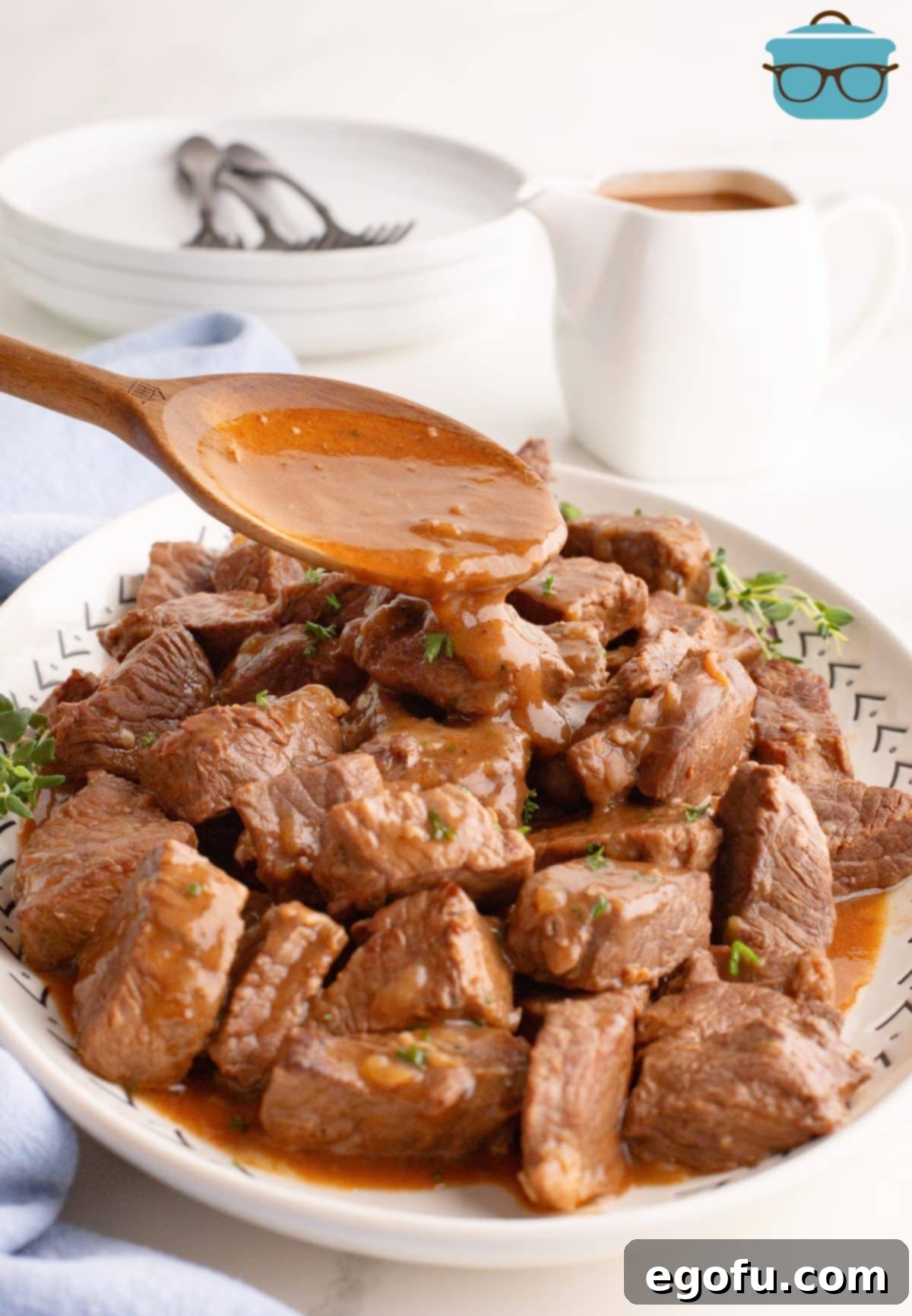 A wooden utensil drizzling gravy over tender Beef Tips.