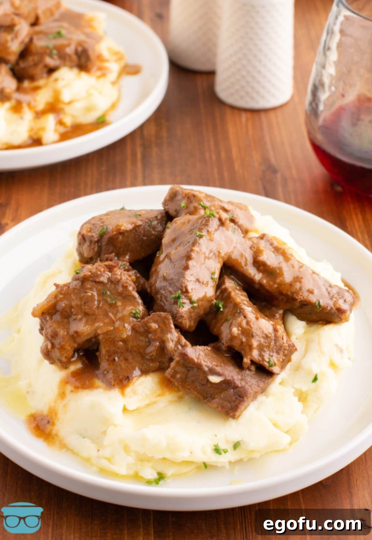 A few Beef Tips and gravy on top of a pile of mashed potatoes.