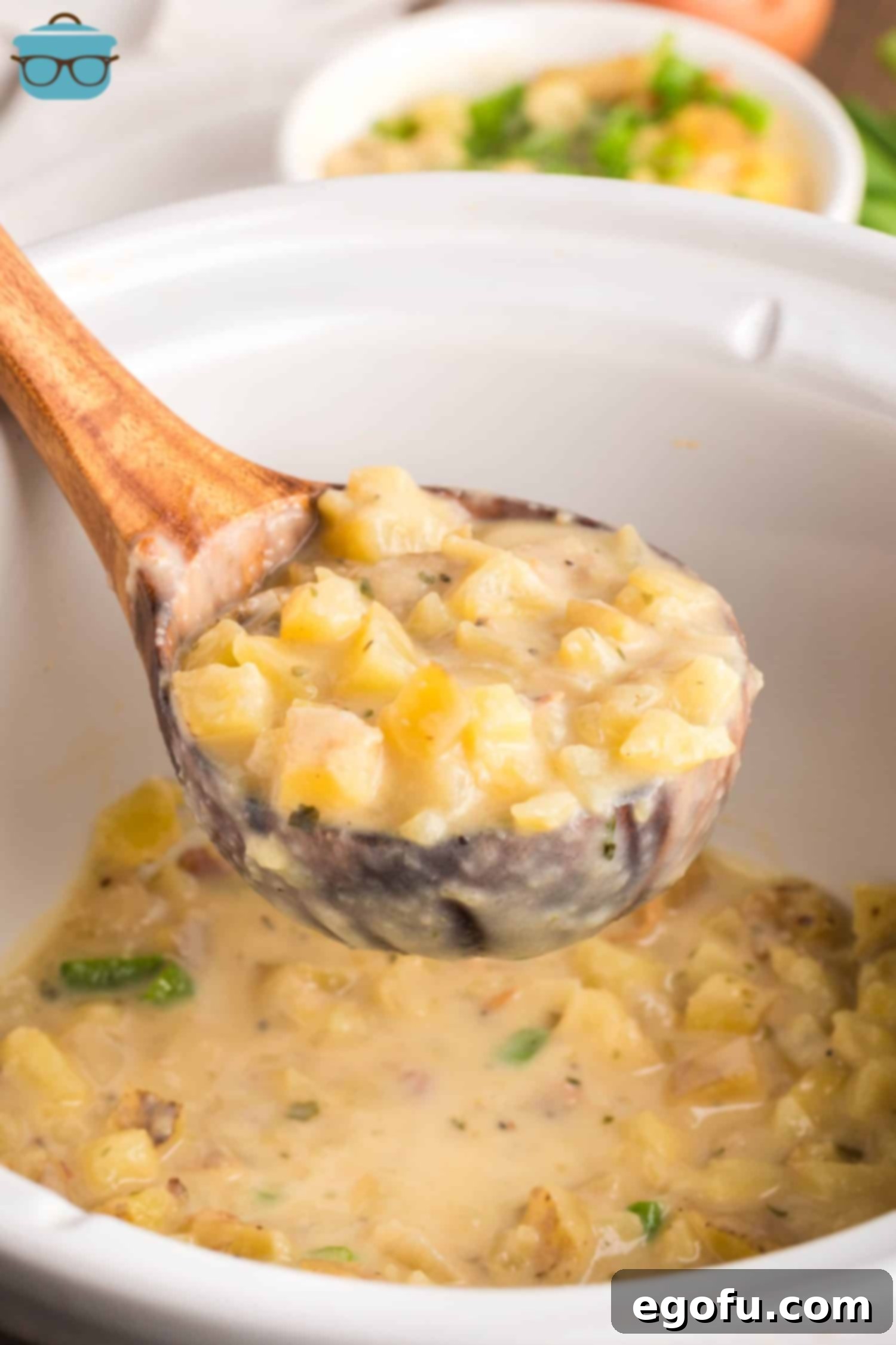 A ladle of creamy Crock Pot Potato Soup, garnished with fresh herbs and bacon, is held above a small slow cooker insert, showcasing the rich texture and hearty ingredients.