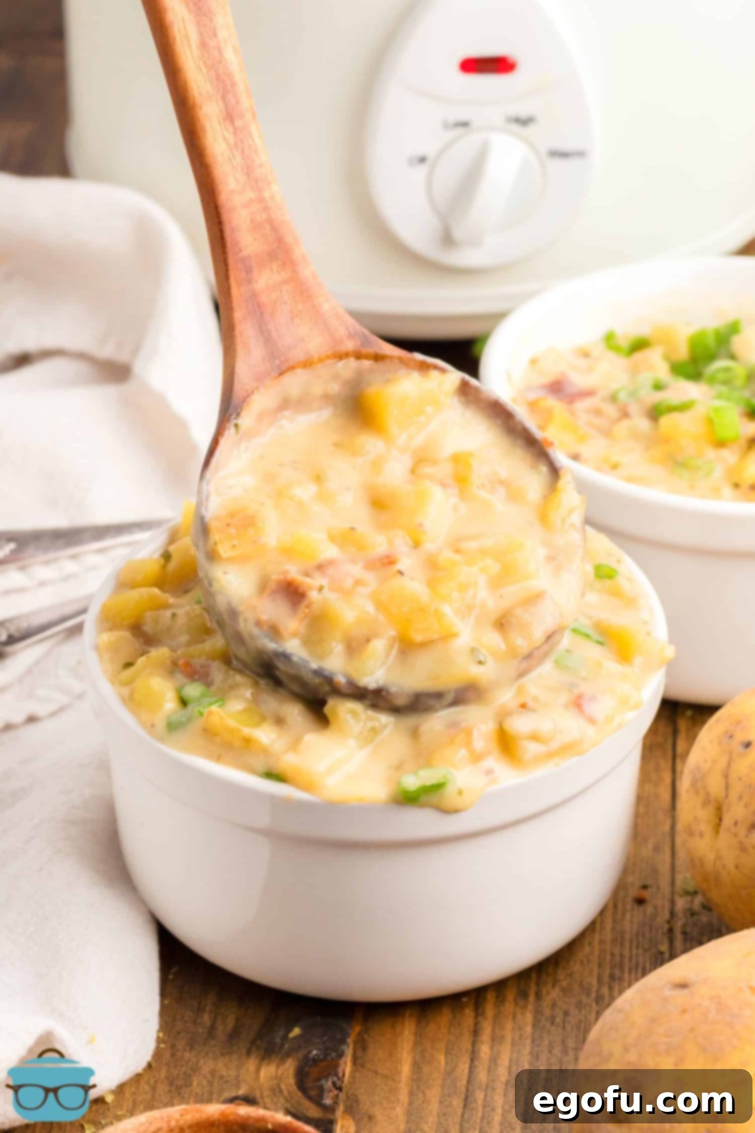 A ladle expertly filling a cup with steaming Crock Pot Potato Soup, ready to be served, showcasing the rich texture and inviting warmth of the finished dish.