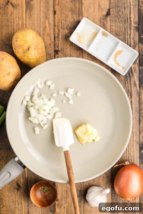 Chopped yellow onion and butter sautéing in a pan until the onions are translucent, preparing the aromatic base for the soup.