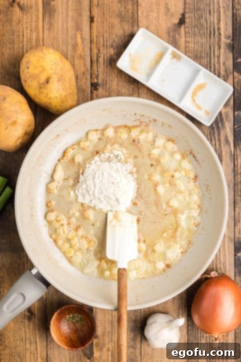 All-purpose flour being stirred into the onion, garlic, and butter mixture in a pan to form a roux, a key step for thickening the soup.