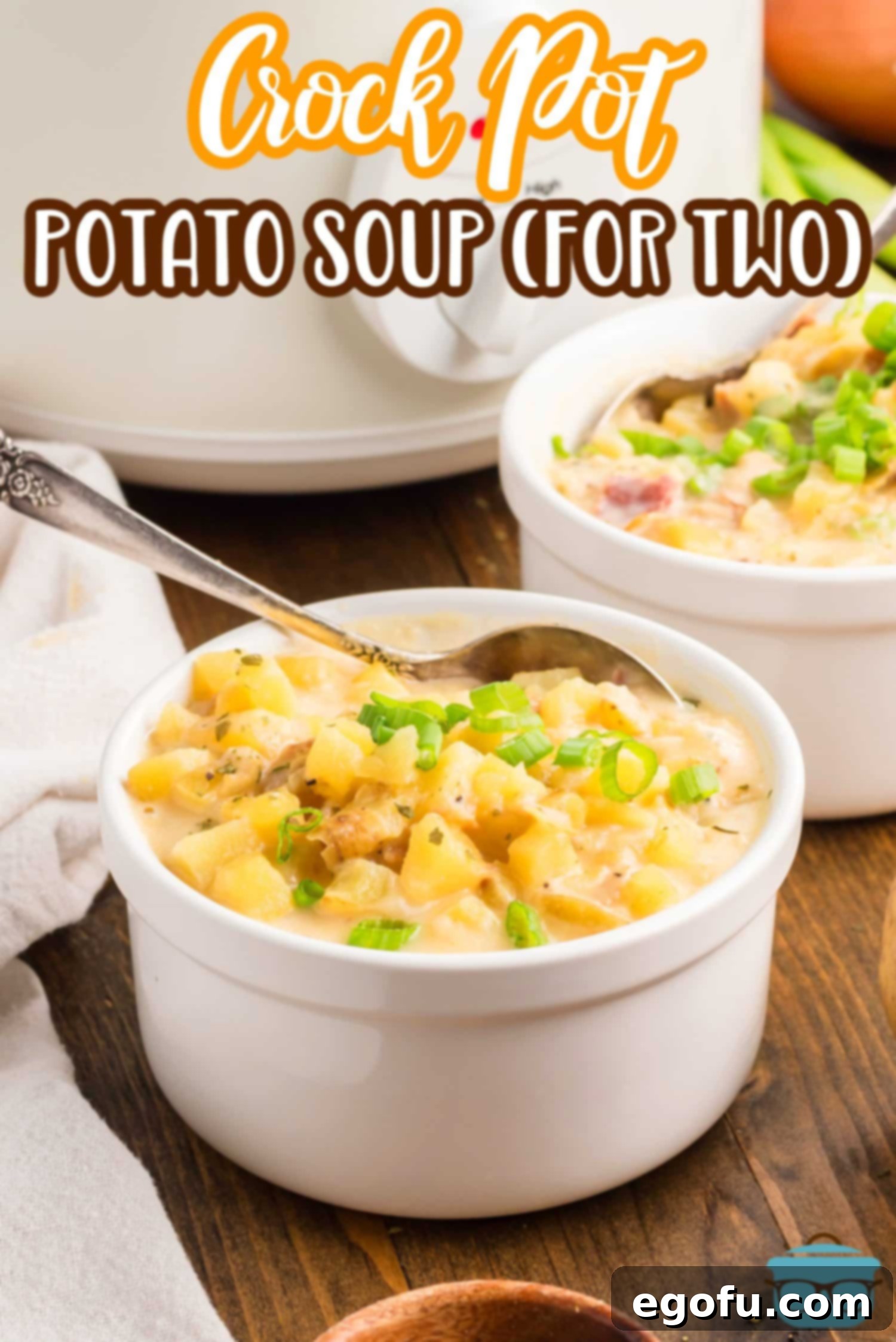 A close-up shot of a spoon scooping a delicious bite of Crock Pot Potato Soup from a bowl, garnished with melted cheese and green onions, highlighting its creamy texture.