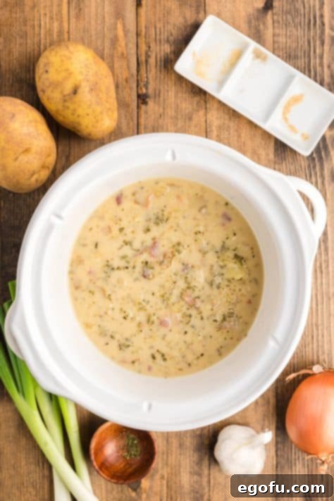 Creamy potato soup simmering in a small slow cooker, showcasing its rich texture after the final cooking stage.