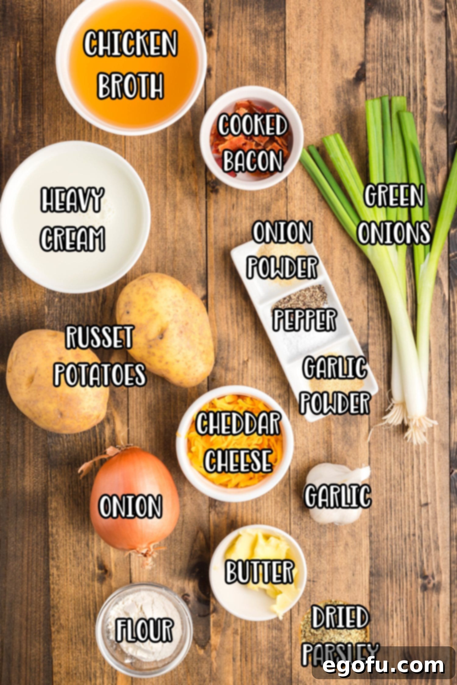 A vibrant flat lay of all the essential ingredients for Crock Pot Potato Soup for Two, including milk, fresh green onions, russet potatoes, low-sodium chicken broth, crispy bacon, fresh parsley, kosher salt, black pepper, onion powder, garlic powder, chopped yellow onion, salted butter, minced garlic cloves, all-purpose flour, and shredded cheddar cheese, beautifully arranged on a rustic surface.