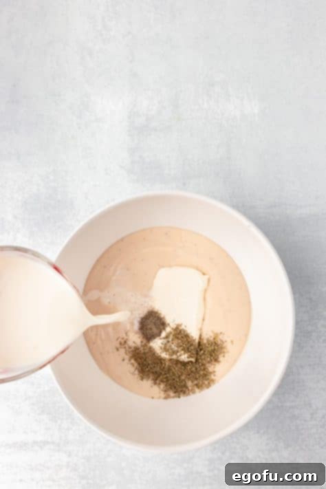 Alfredo sauce mixture being stirred in a bowl.
