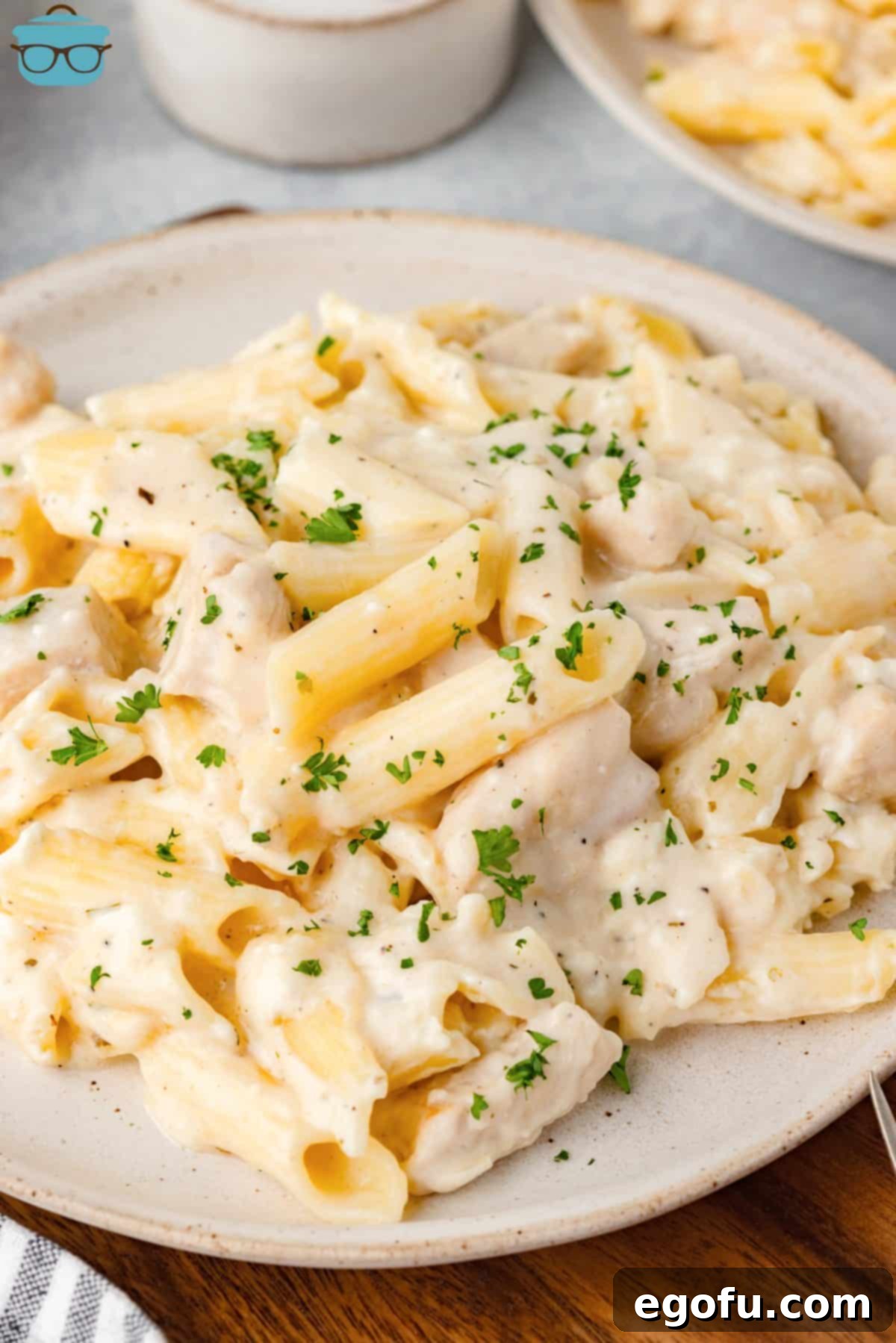 A large dinner plate of Chicken Alfredo Casserole, garnished with fresh parsley.