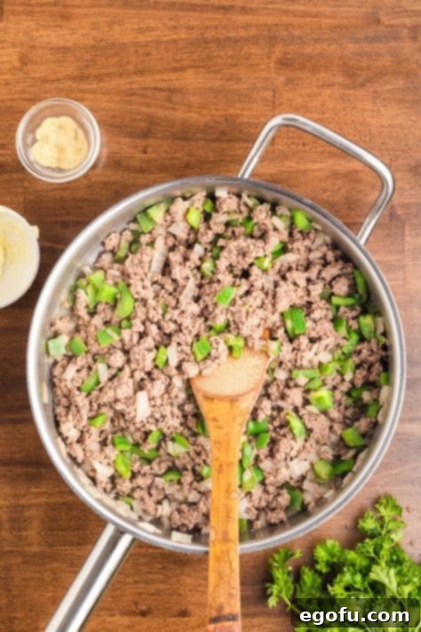 Ground beef, onions, and peppers cooked in a skillet.