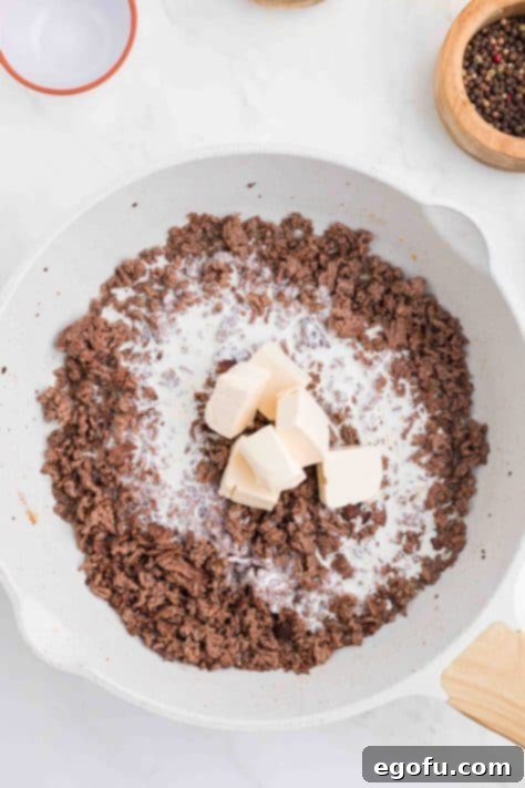 Heavy cream and cream cheese being added to beef.