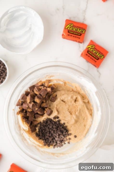 Chocolate chips and Reese's peanut butter cups being added to fluff.