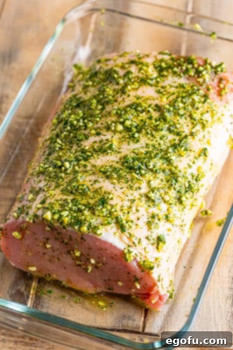 Herb crusted uncooked pork roast in a baking dish.