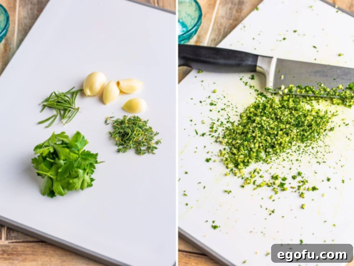 A cutting board with garlic, parsley, thyme, and rosemary being chopped together into a fine mixture.