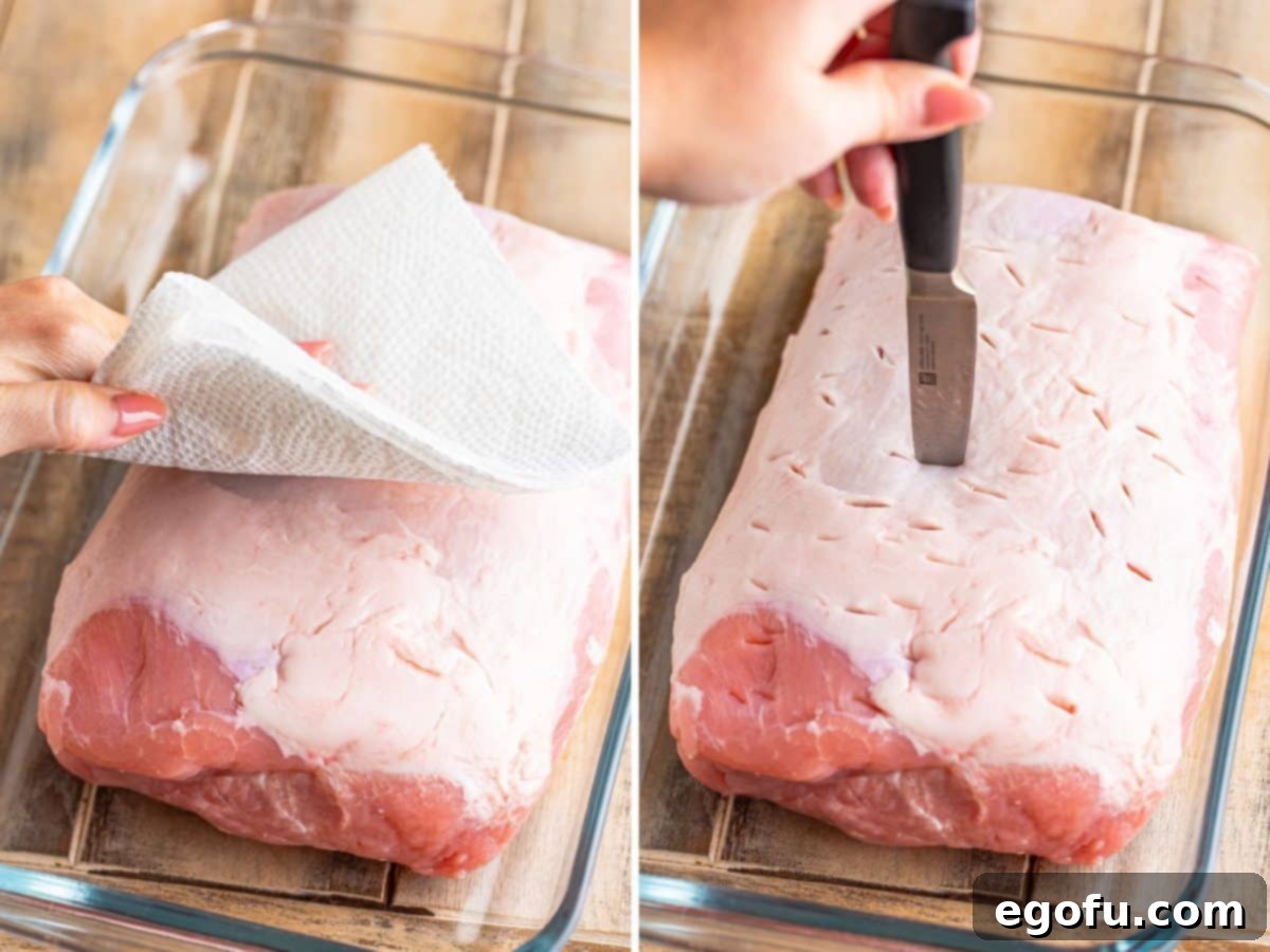 A hand patting a pork roast dry with paper towels, and another hand poking holes into the roast with a paring knife.