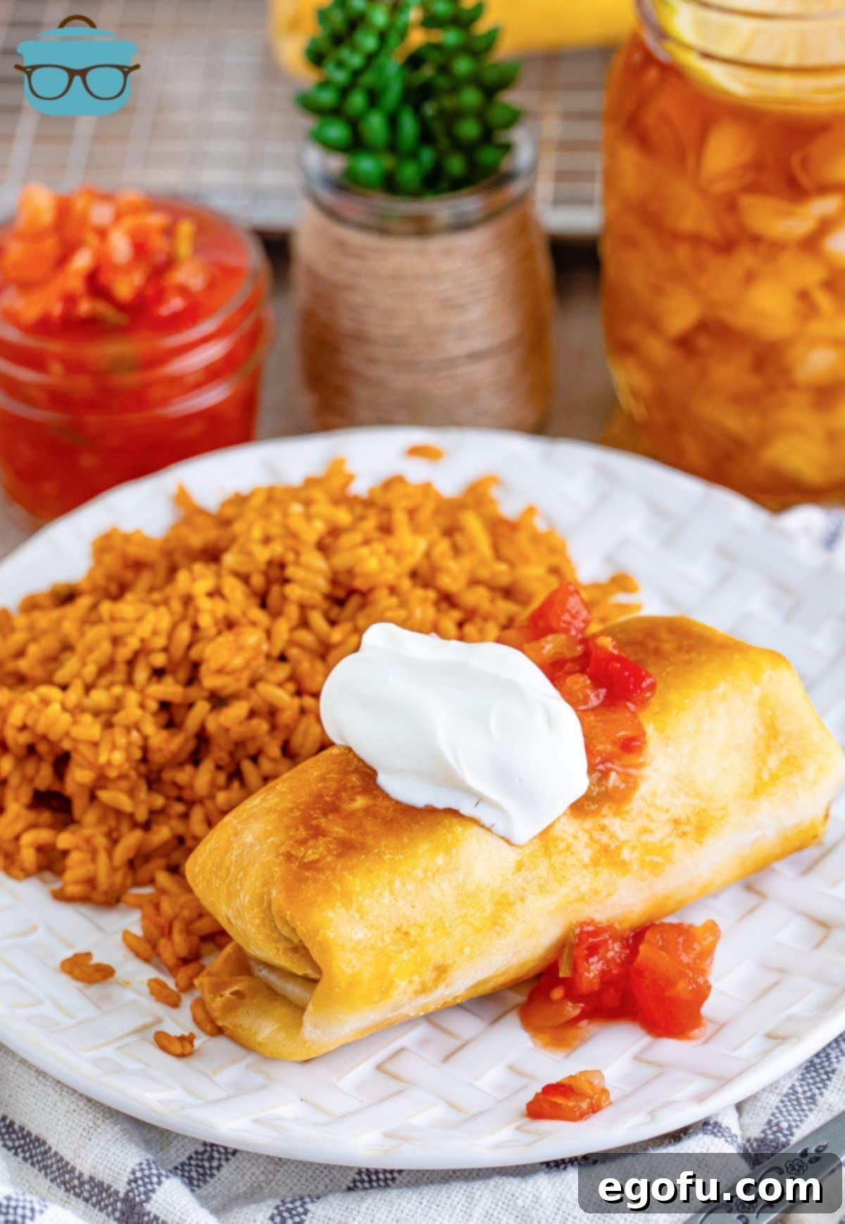 A golden-brown Chicken Chimichanga served elegantly on a plate with Spanish rice, garnished with fresh cilantro, ready to be enjoyed.